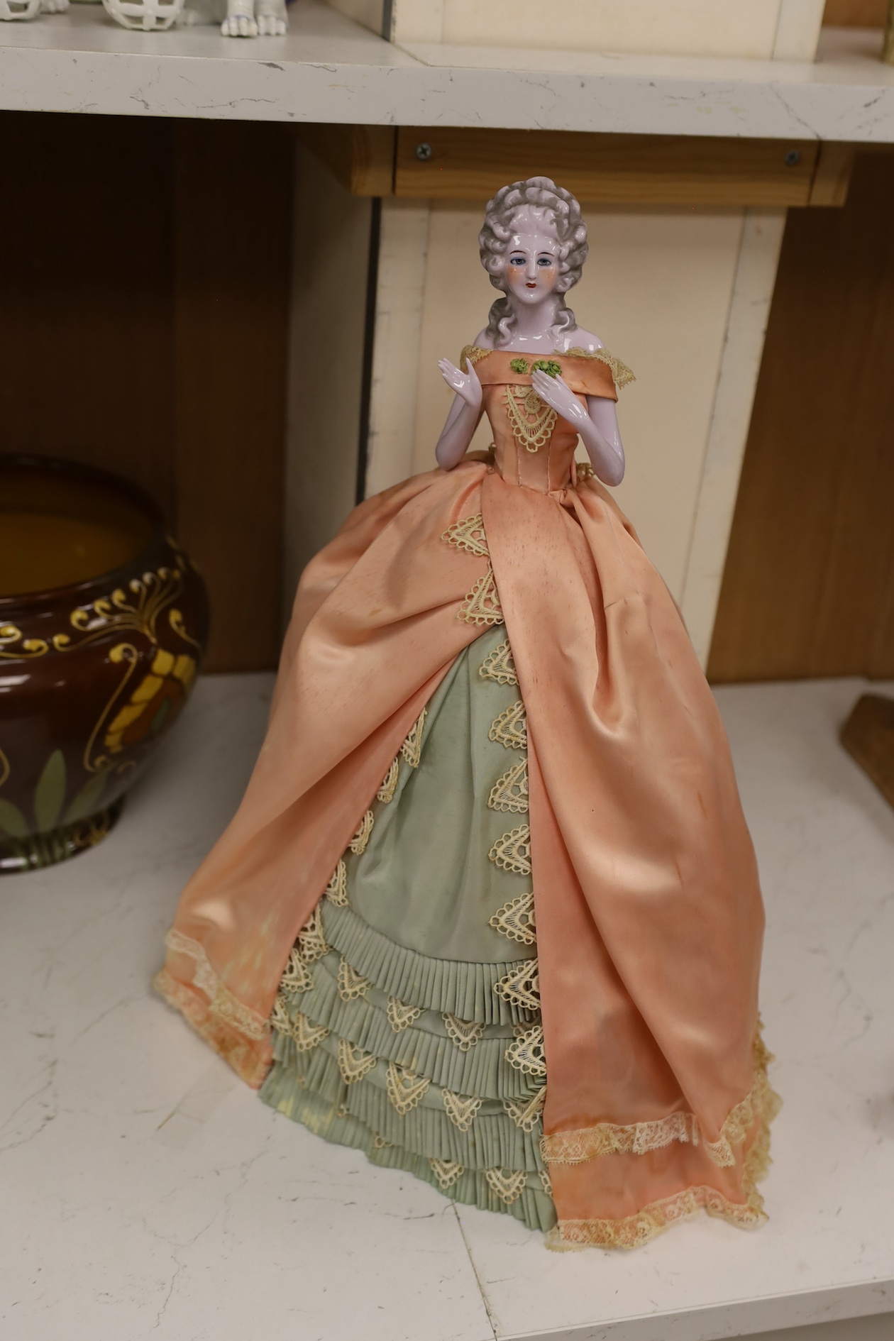 A 1920’s German porcelain 'pin dolly' with tea cosy dress, 46cm high. Condition - good some marks to the silk of cosy/dress